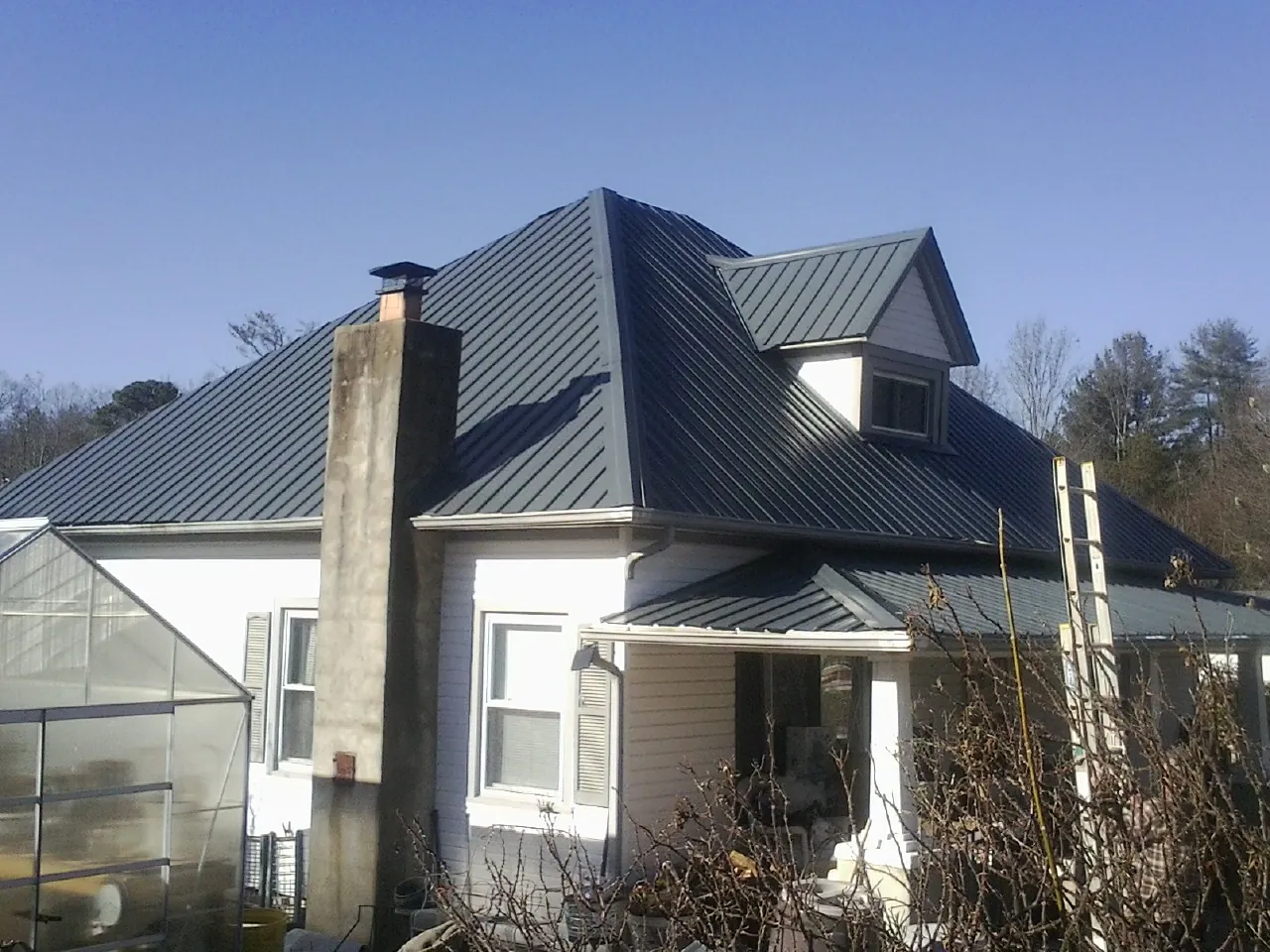 Dark blue standing seam metal roof on a white farmhouse with dormer — Slate & Tile Roof Repair by Roofing Brothers in Diamond Bar