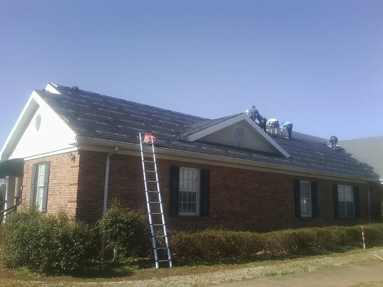 Crew tearing shingles off a brick ranch roof with a ladder set — Metal Roof Repair work by our crew in Diamond Bar