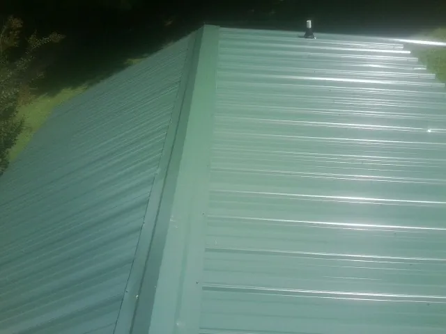 New green metal panels meeting at the ridge of a roof — Flat Roof Repair work by our crew in Diamond Bar
