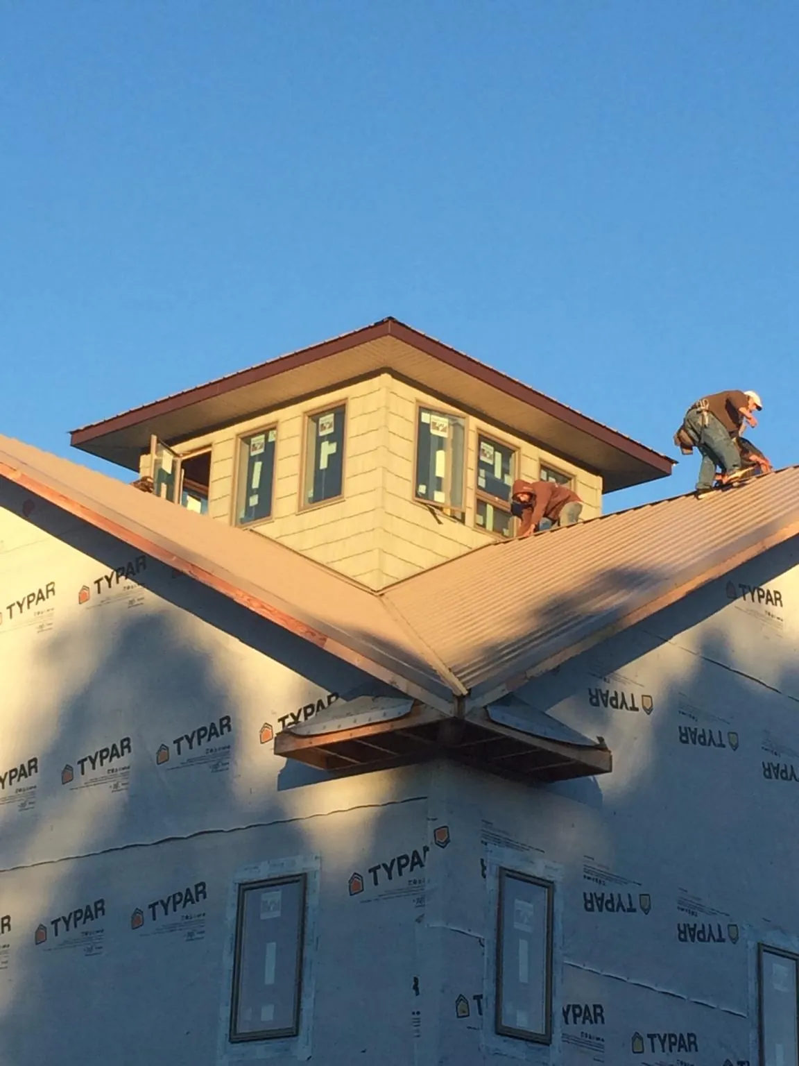 Roofers working around a rooftop cupola on a new metal roof at sunset — Roof Waterproofing in Diamond Bar by Roofing Brothers